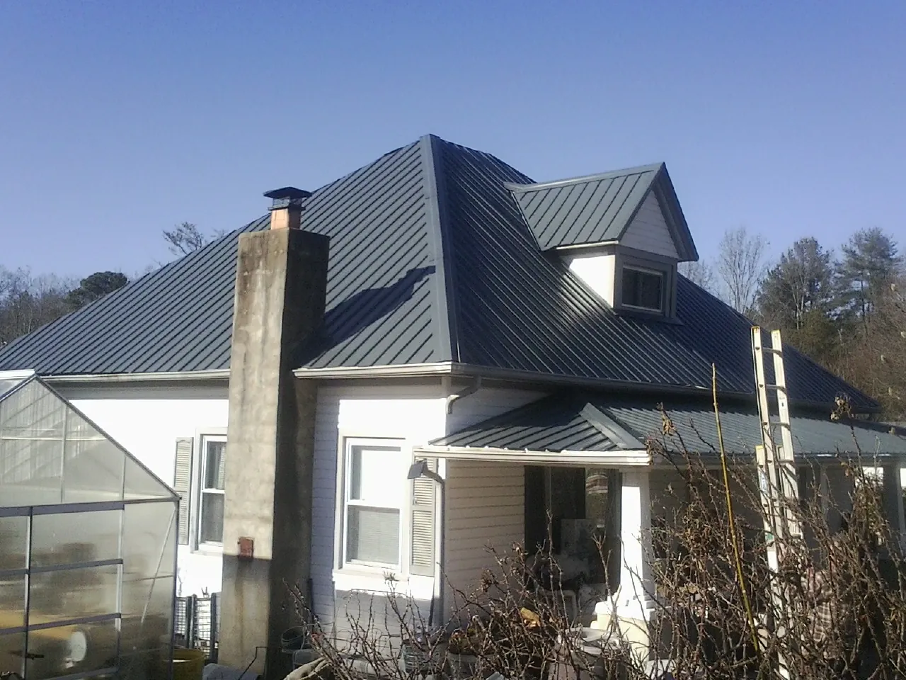 Dark blue standing seam metal roof on a white farmhouse with dormer — Slate & Tile Roof Repair by Roofing Brothers in Mount Crawford