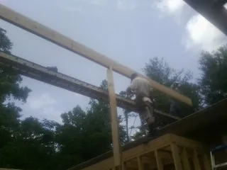 Carpenter setting a ridge beam over a new addition frame — Ice Dam Removal by Roofing Brothers in Mount Crawford