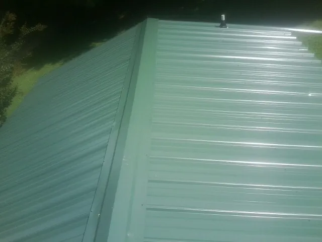 New green metal panels meeting at the ridge of a roof — Flat Roof Repair work by our crew in Mount Crawford