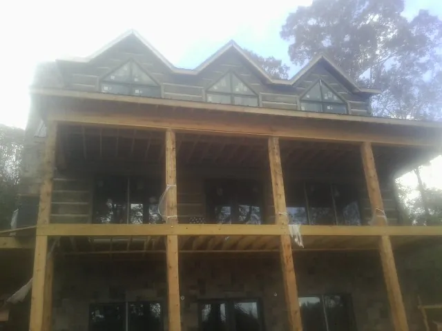 Dormers and porch framing on a large log home under construction — Roof Coating work by our crew in Mount Crawford