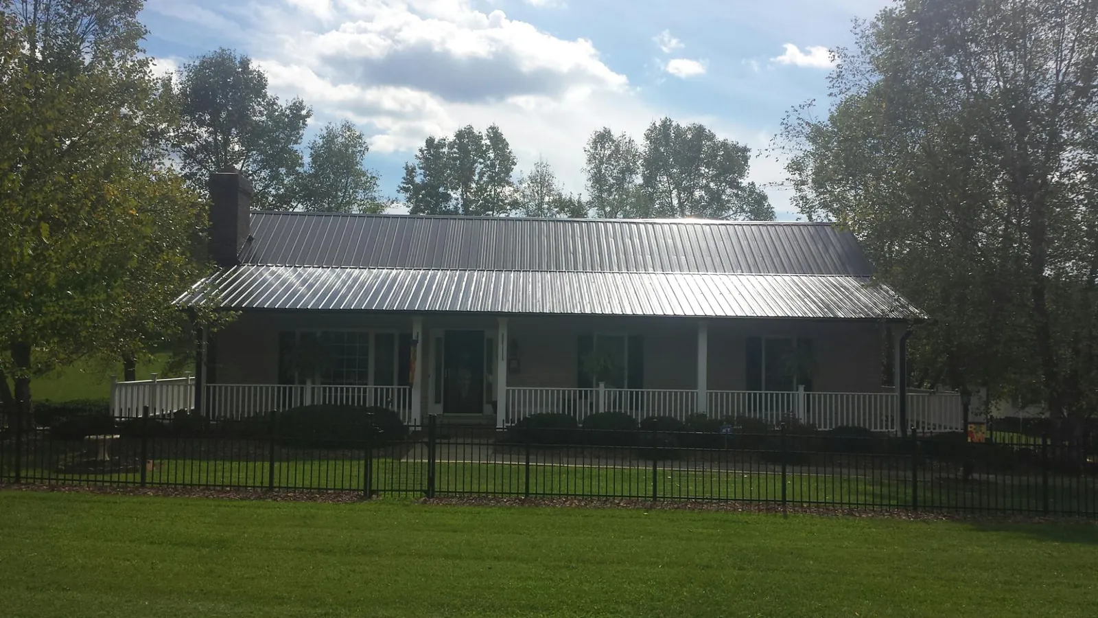 Gray metal roof on a brick ranch with a full width front porch — Gutter Guard Installation work by our crew in Mount Crawford