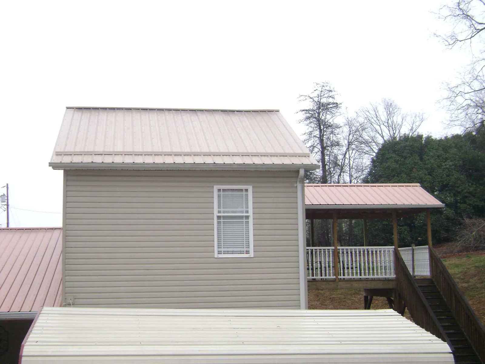 Tan metal roofs on a two story addition and attached porch, from a Roof Replacement job in Mount Crawford