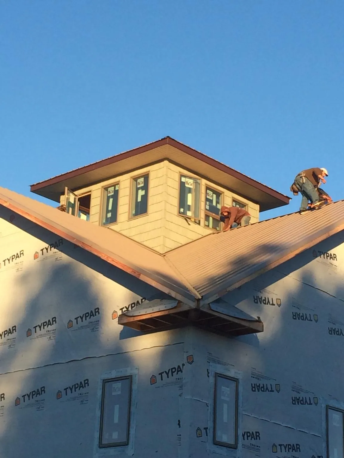 Roofers working around a rooftop cupola on a new metal roof at sunset — Roof Waterproofing in Mount Crawford by Roofing Brothers